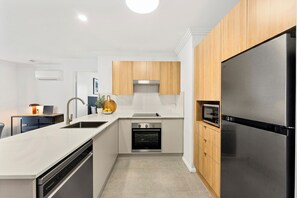 Una cocina moderna con un refrigerador de acero inoxidable, un horno empotrado y gabinetes de madera.