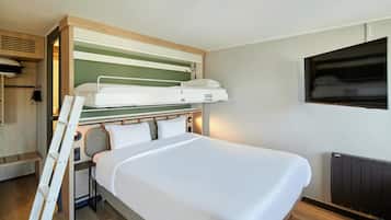 Une chambre d’hôtel compacte avec un lit superposé, un téléviseur à écran plat fixé au mur et un plancher en bois.