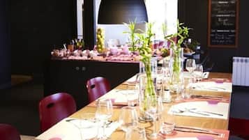 A restaurant with a long wooden table set for dining, featuring clear glassware and cutlery.