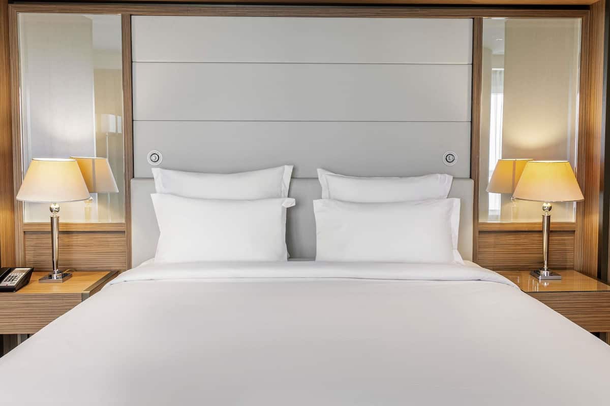 A hotel room with a large bed, two bedside tables, lamps, and a mirror.