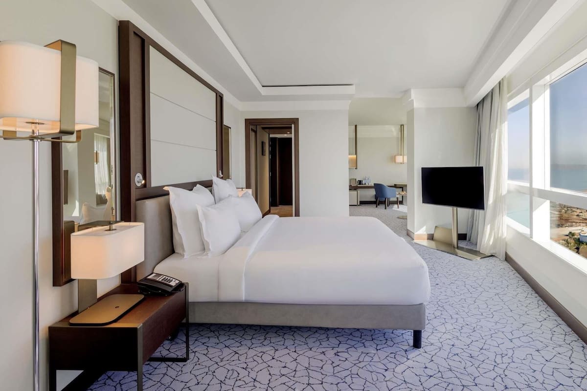 A hotel room with a large bed, bedside table, lamp, and a TV.