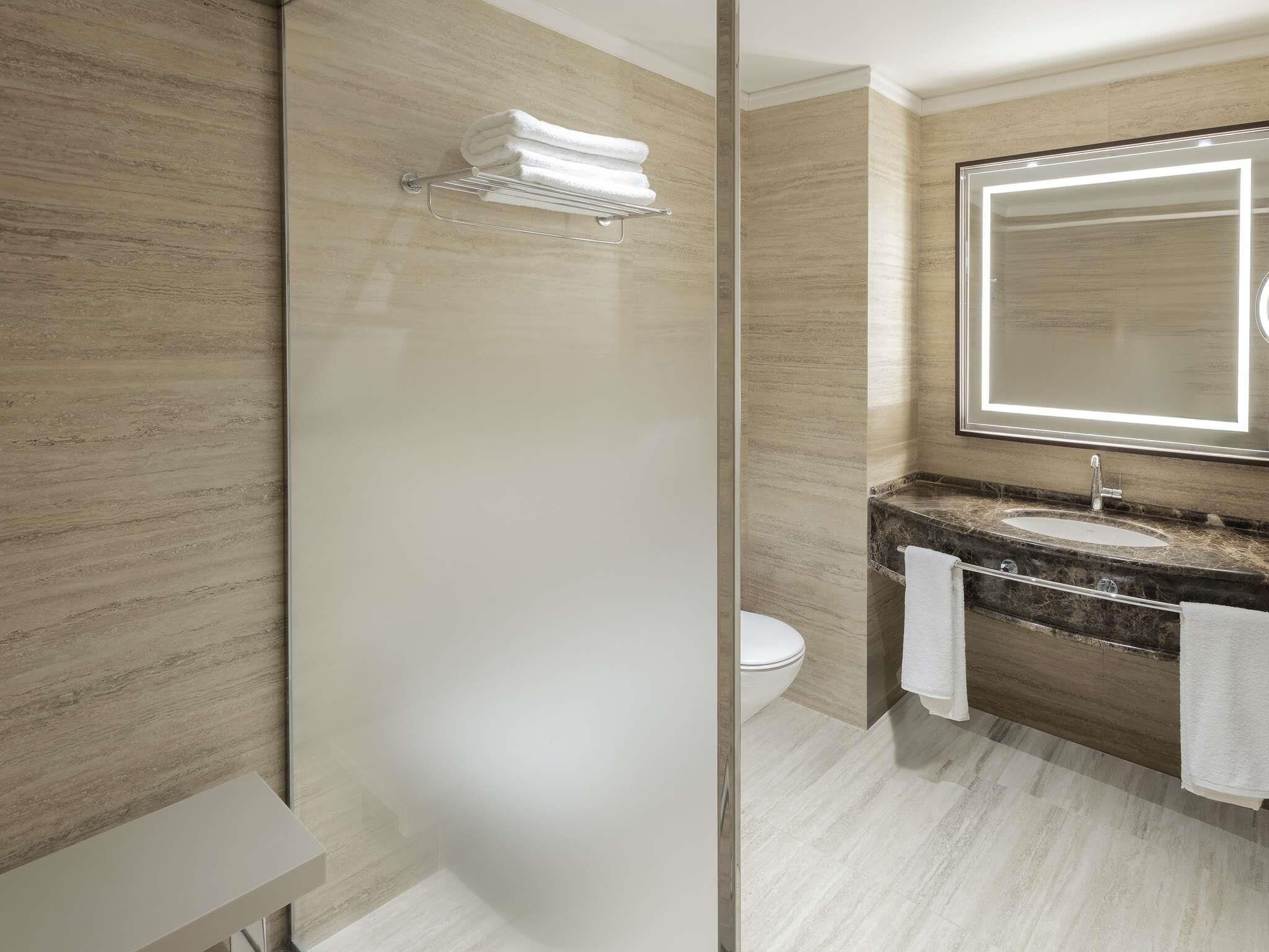 Un bagno moderno con cabina doccia in vetro, lavabo in marmo e uno specchio grande.
