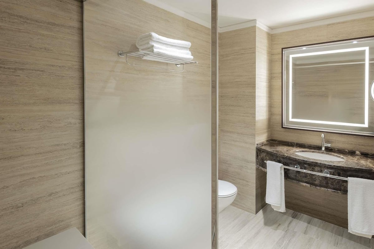 Une salle de bain moderne avec une douche Ă parois de verre, un lavabo en marbre et un grand miroir.