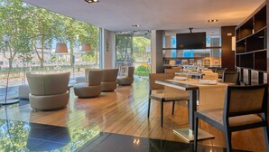 Un interior moderno con comedor, asientos y un amplio ventanal con vistas al exterior.