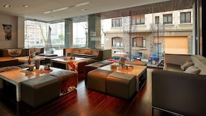 Un salón moderno con asientos de cuero, una mesa de centro de madera y grandes ventanales con vistas a la ciudad.