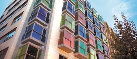 A multi-story building with a modern architectural design, featuring a series of balconies and large windows.