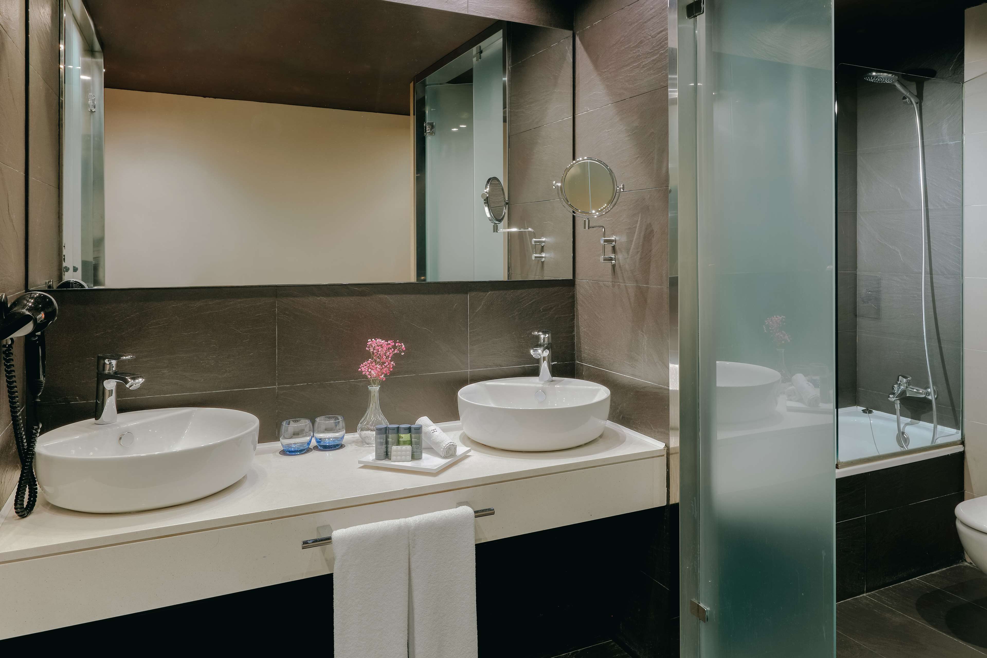 Une salle de bain moderne avec deux lavabos, un miroir et une douche à parois de verre.
