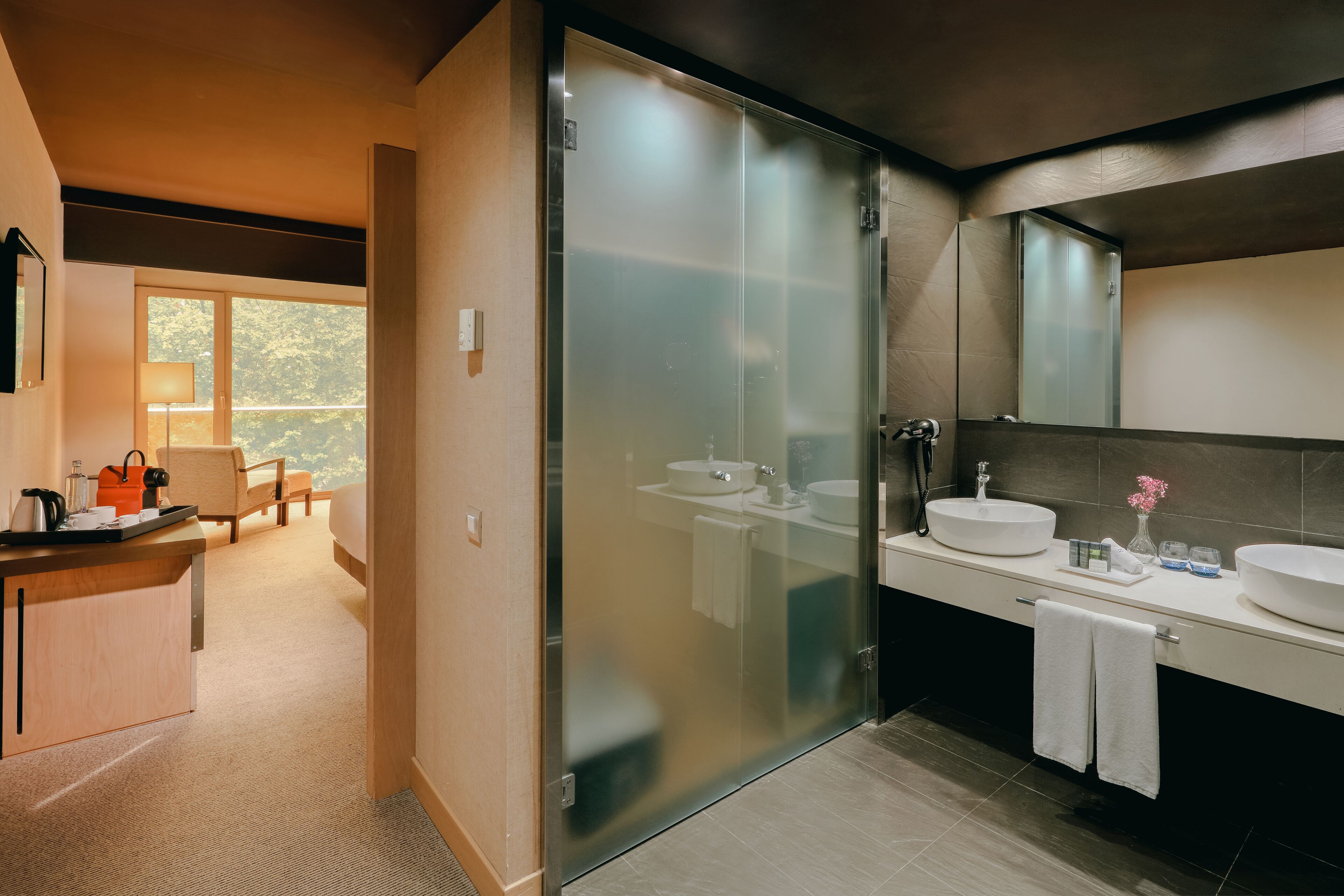 Une salle de bain moderne avec un grand miroir, deux vasques et une douche à l’italienne.
