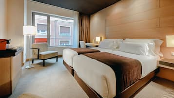 Una camera d'albergo con un letto grande, una scrivania, una sedia e una finestra vista edifici.