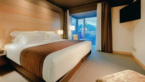 Habitación de hotel con una cama grande, un televisor de pantalla plana y vistas al exterior a través de un ventanal amplio.
