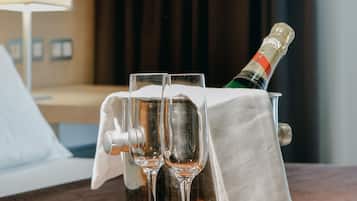 Una bandeja de madera con dos copas y una botella de champán sobre una cama de hotel.