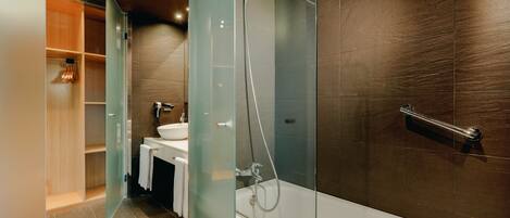 Un baño moderno con ducha de vidrio, bañera y tocador con lavamanos.