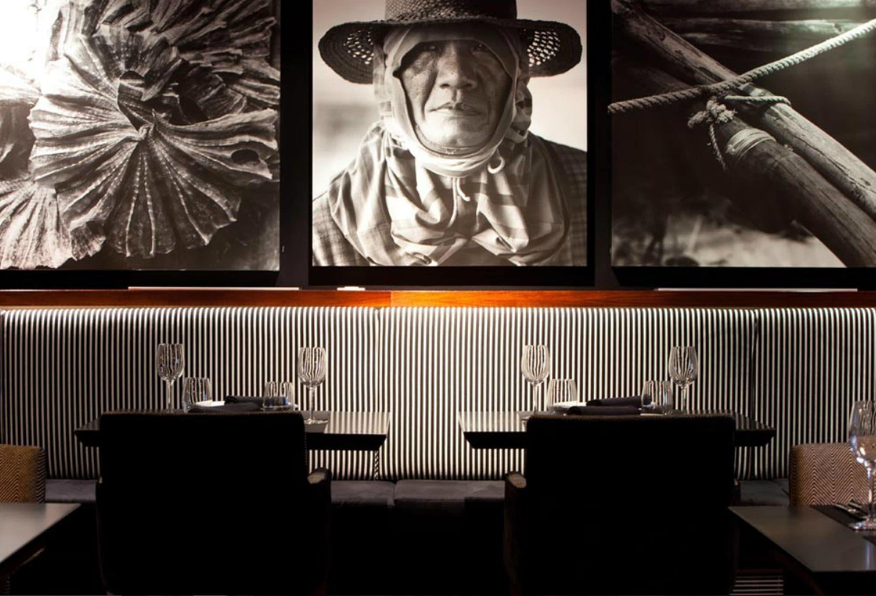 A restaurant with a striped wall, a framed picture of a person in a hat, and a rope tied around a wooden beam.