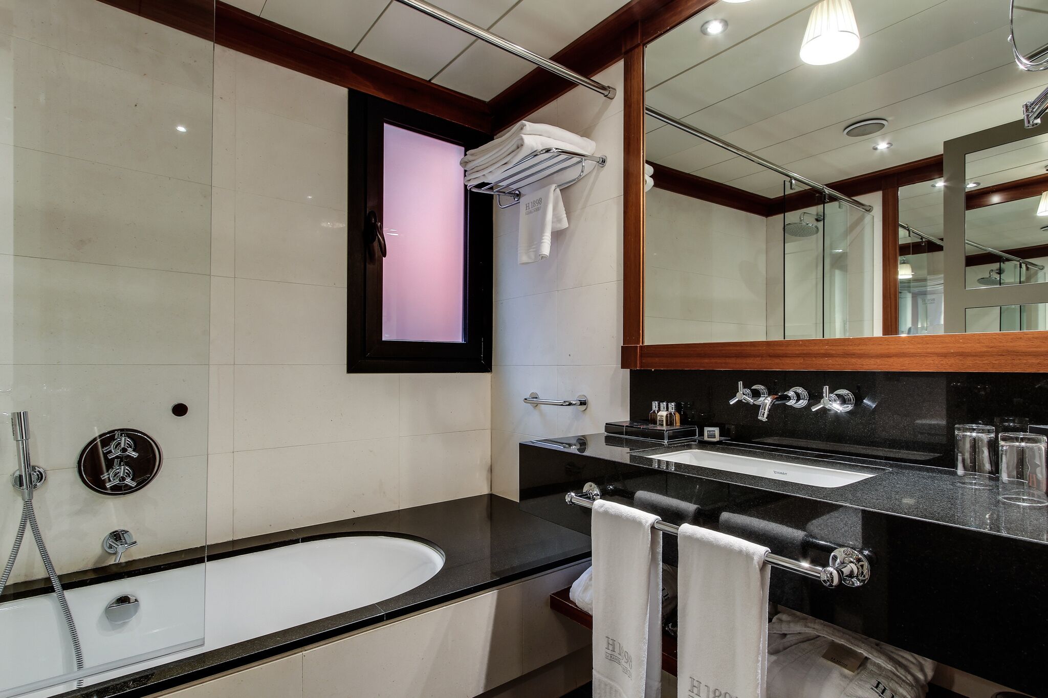 Une salle de bain moderne avec un grand miroir, une baignoire et deux lavabos.