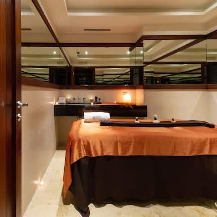 A hotel room with a large bed, a wooden door, a mirror, and a small table with toiletries.