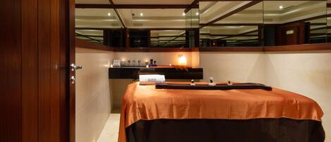 A hotel room with a large bed, a wooden door, a mirror, and a small table with toiletries.