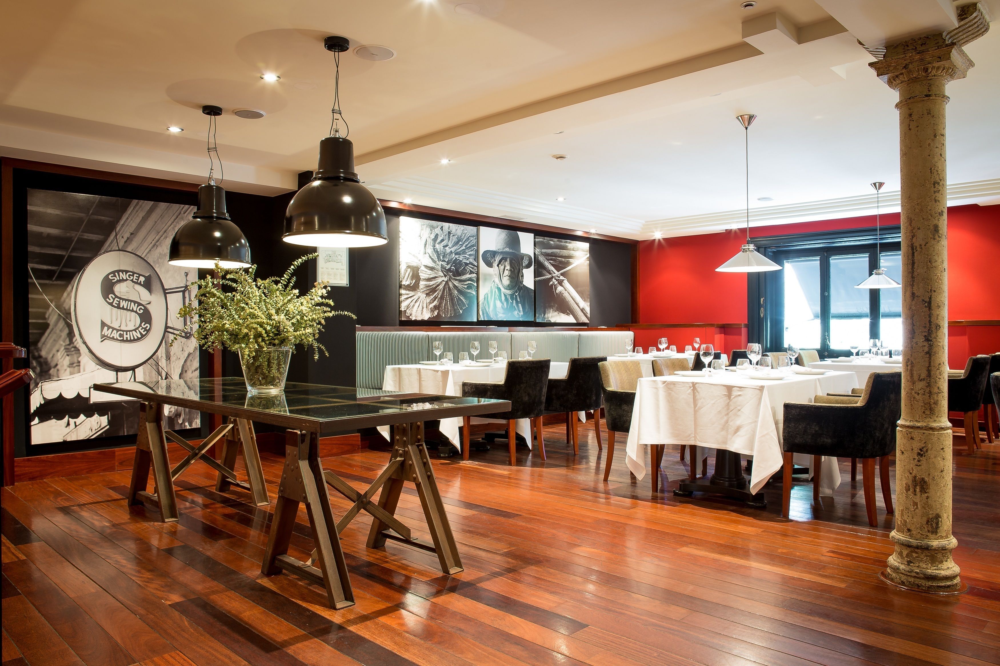 Un restaurante con suelo de madera, mesas dispuestas para comer y lámparas colgantes.