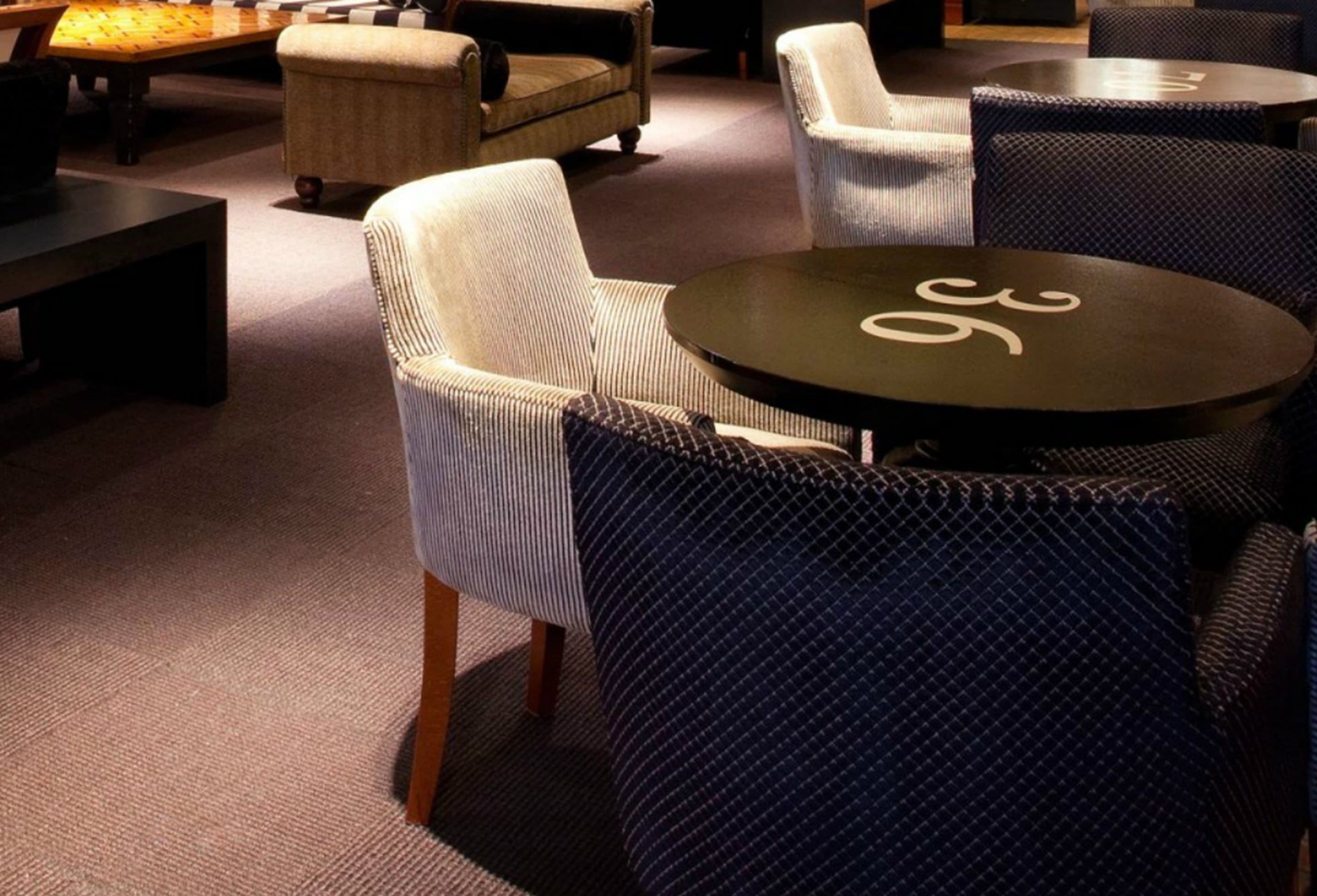 A cozy lounge area with a round table, cushioned seating, and a patterned rug.