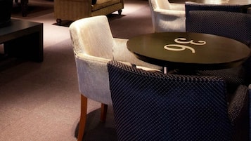 A cozy lounge area with a round table, cushioned seating, and a patterned rug.