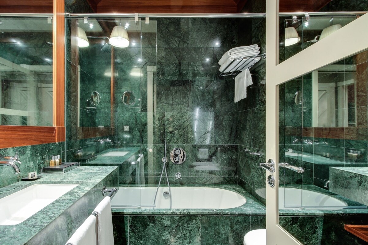 A modern bathroom with two sinks, a bathtub, and a glass-enclosed shower area.