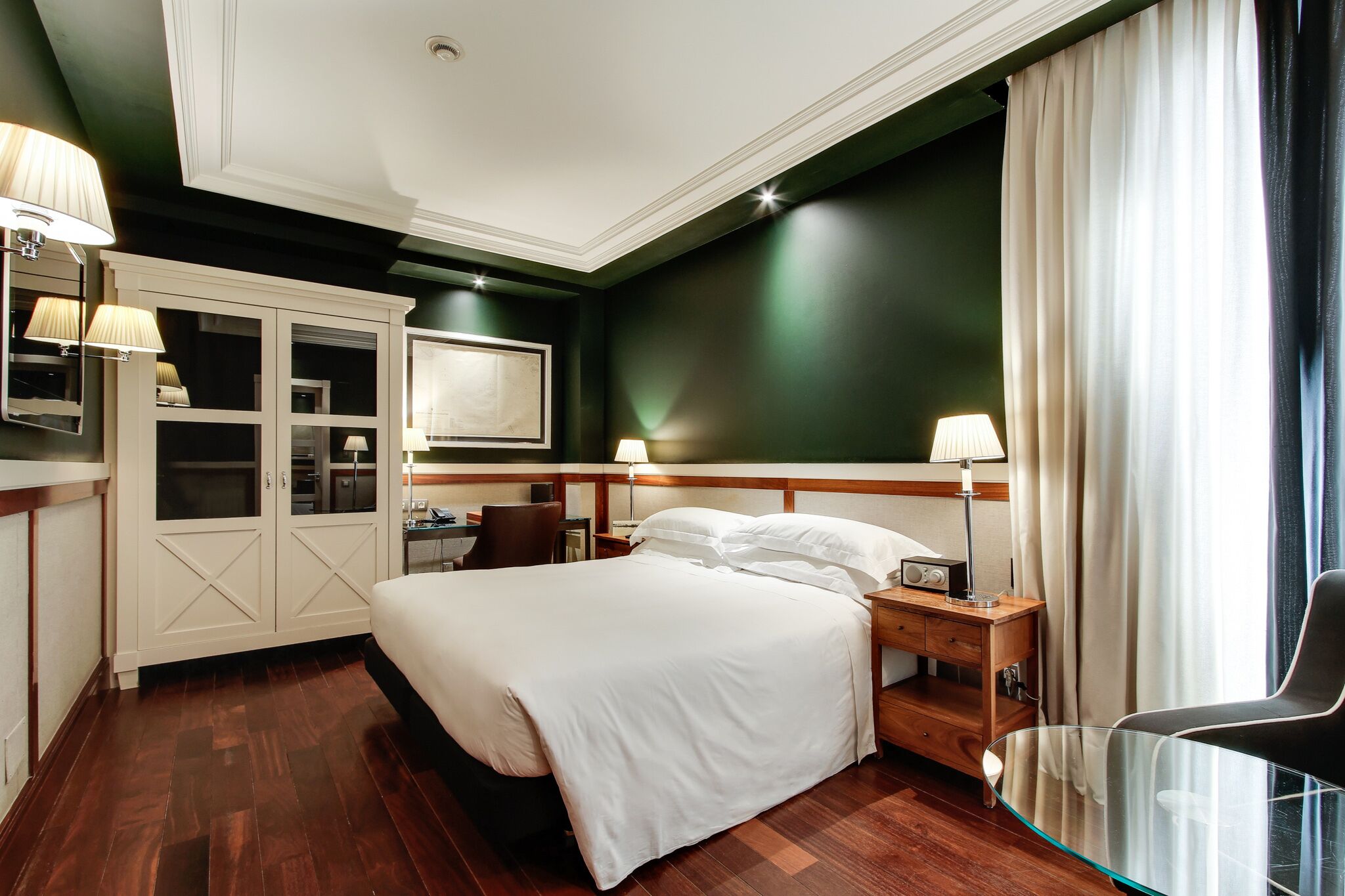 A hotel room with a large bed, bedside tables, a desk, and a chair.