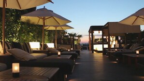 A rooftop lounge area with multiple seating options, including sofas and chairs, under large umbrellas. - Hotel 1898 (Barcelona)