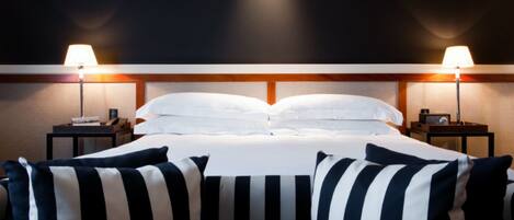 Una habitación de hotel con una cama grande, dos mesitas de noche y dos lámparas.