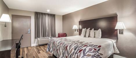 Une chambre d’hôtel avec un lit, des lampes de chevet, un bureau et une chaise.