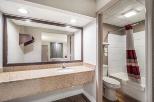 A bathroom with a granite countertop sink, a mirror, a toilet, and a shower with a striped curtain.