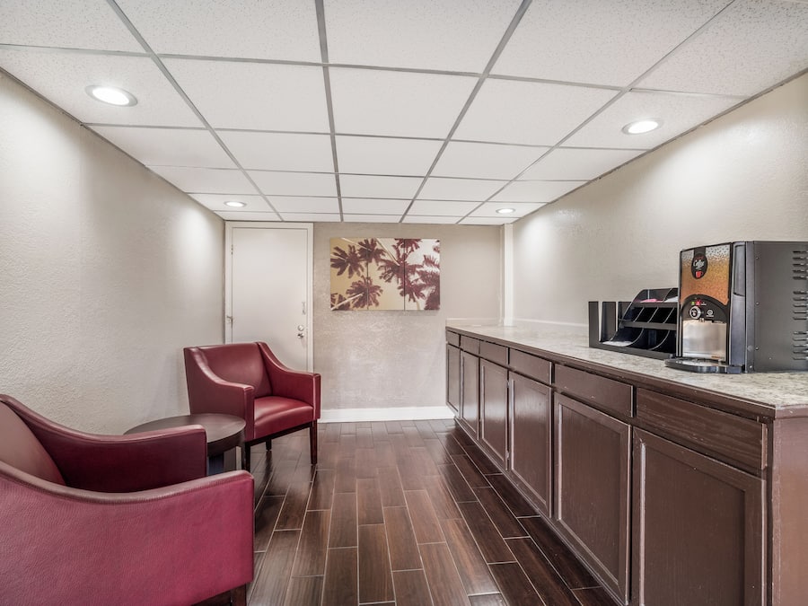 Een hotel lobby met een zithoek, een koffiehoek en een muur met een kunstwerk van een palmboom.