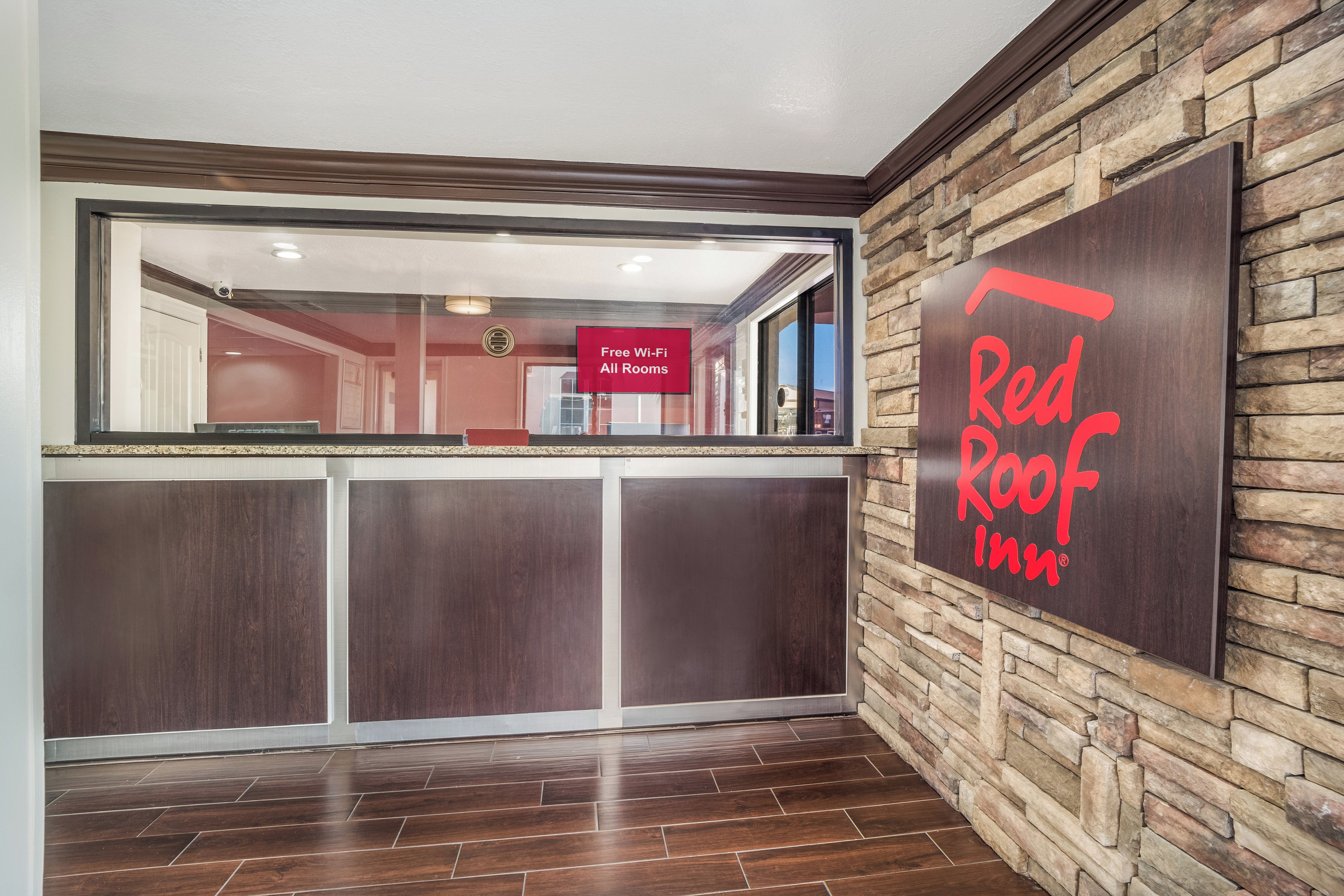 A reception area with a stone wall and a Red Roof Inn sign.