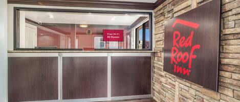 A reception area with a stone wall and a Red Roof Inn sign.