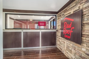A reception area with a stone wall and a Red Roof Inn sign. - Red Roof Inn Sumter (Sumter)