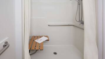 Un espace douche avec un banc en bois, une serviette et un pommeau de douche.