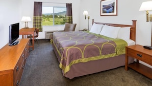 A hotel room with a bed, a desk with a TV, a chair, and a window with curtains. - Super 8 by Wyndham Central Pt Medford (Central Point)