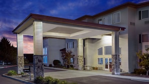 A two-story building with a covered entrance, stone pillars, and a landscaped front yard. - Super 8 by Wyndham Central Pt Medford (Central Point)