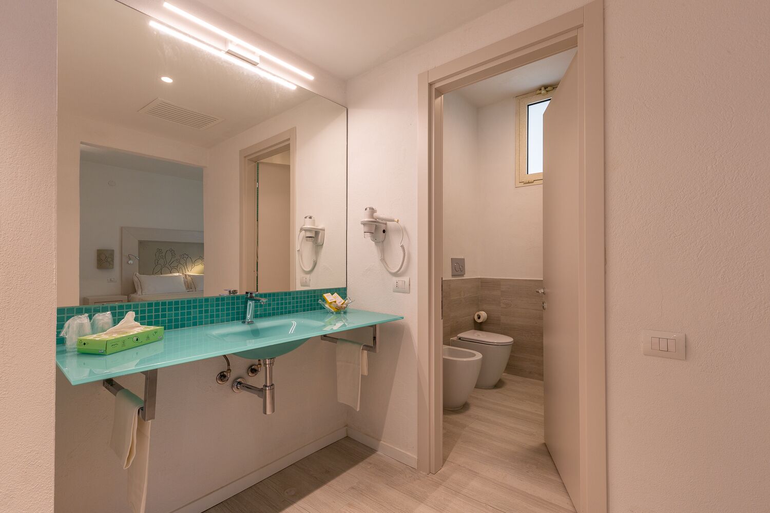 A modern bathroom with a glass sink, a mirror, a shower, and a toilet.