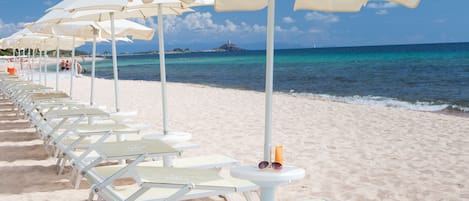 Een privéstrand, ligstoelen aan het strand, parasols