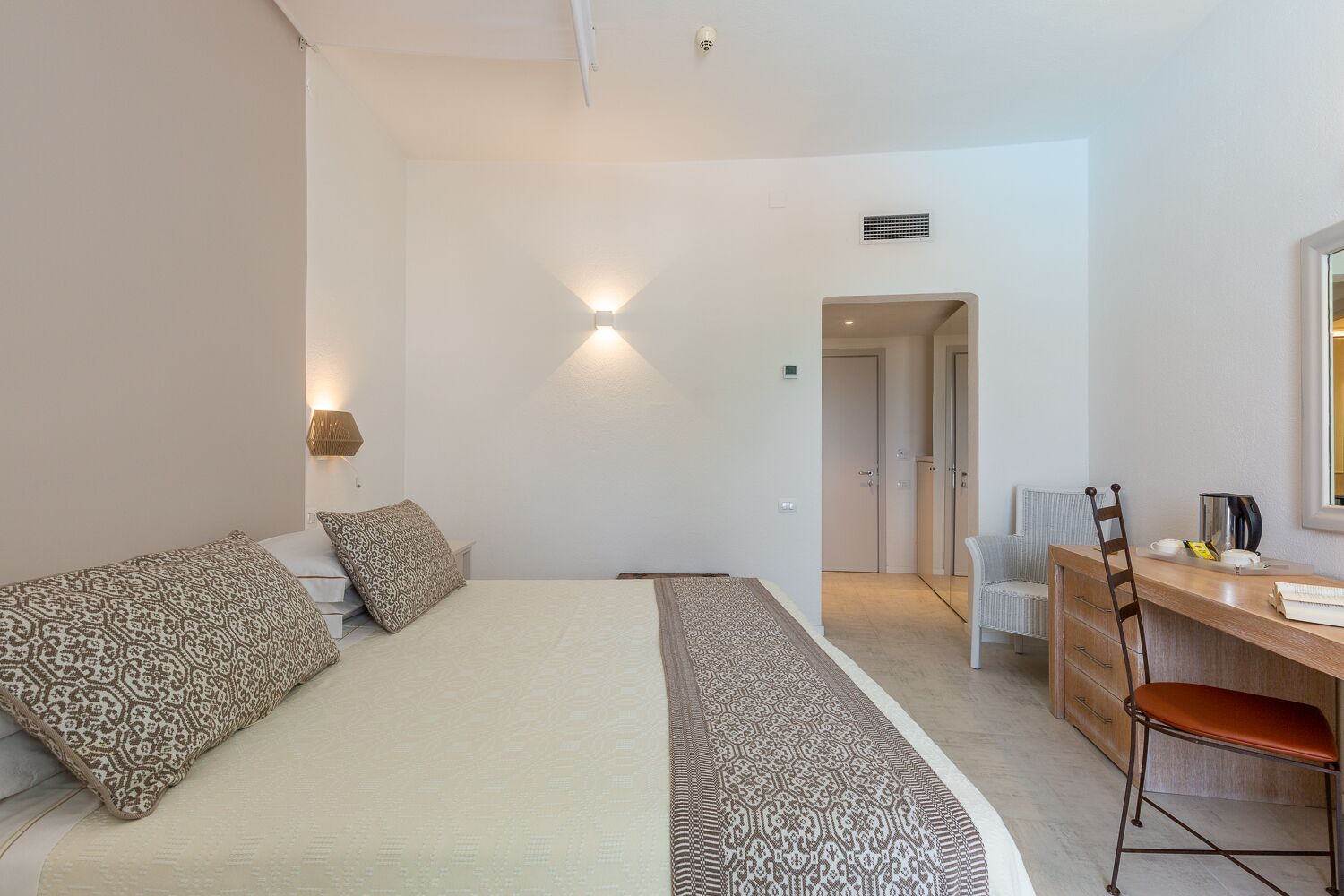 Quarto com cama, mesas de cabeceira, escrivaninha e cadeira.