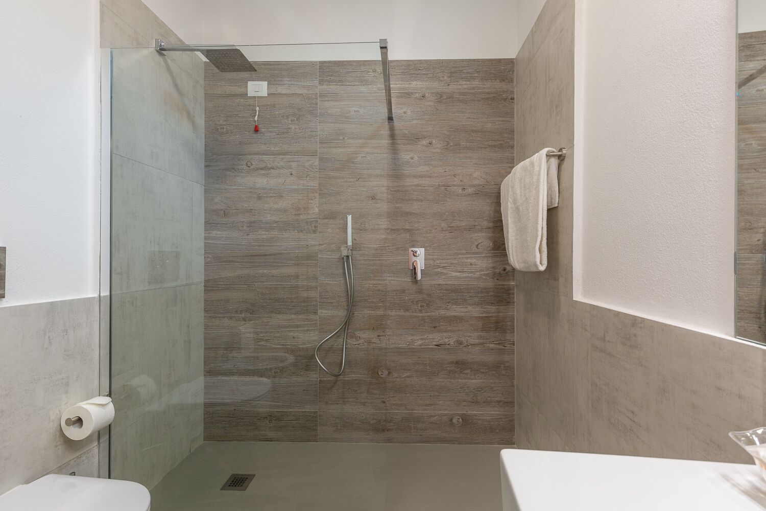 Un baño moderno con cabina de ducha de vidrio, inodoro y lavamanos.