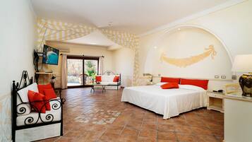 Ein Hotelzimmer mit Bett, Sofa, Schreibtisch, Fernseher und Blick ins Freie.