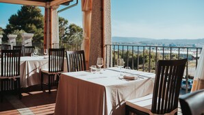 Un restaurant avec des tables dressées pour le service, une terrasse et une vue sur la ville.