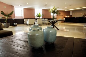 Una zona de recepción con una mesa de madera, dos jarrones de cerámica y un mostrador de recepción.