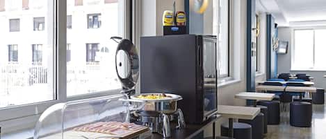 Una barra de desayuno con bufé, un refrigerador y vistas a edificios a través de amplios ventanales.