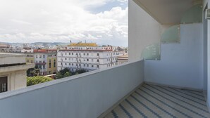 Ein Balkon mit Fliesenboden und Blick auf Gebäude in der Ferne.