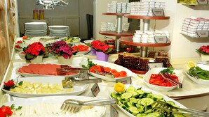 A buffet with various food items, including meats, cheeses, and salads, arranged on a table with serving utensils. - Anzac Hotel (Çanakkale)