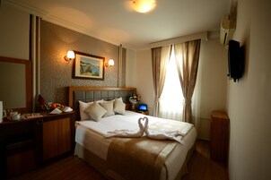 Una habitación de hotel con una cama grande, un escritorio con computadora y un televisor montado en la pared.