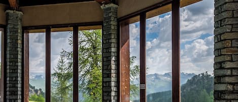 A swimming pool with a clear view of mountains through large windows.