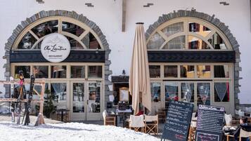 A restaurant with a sign reading 'Chez Laurentine,' outdoor seating with tables and chairs, and a menu board.