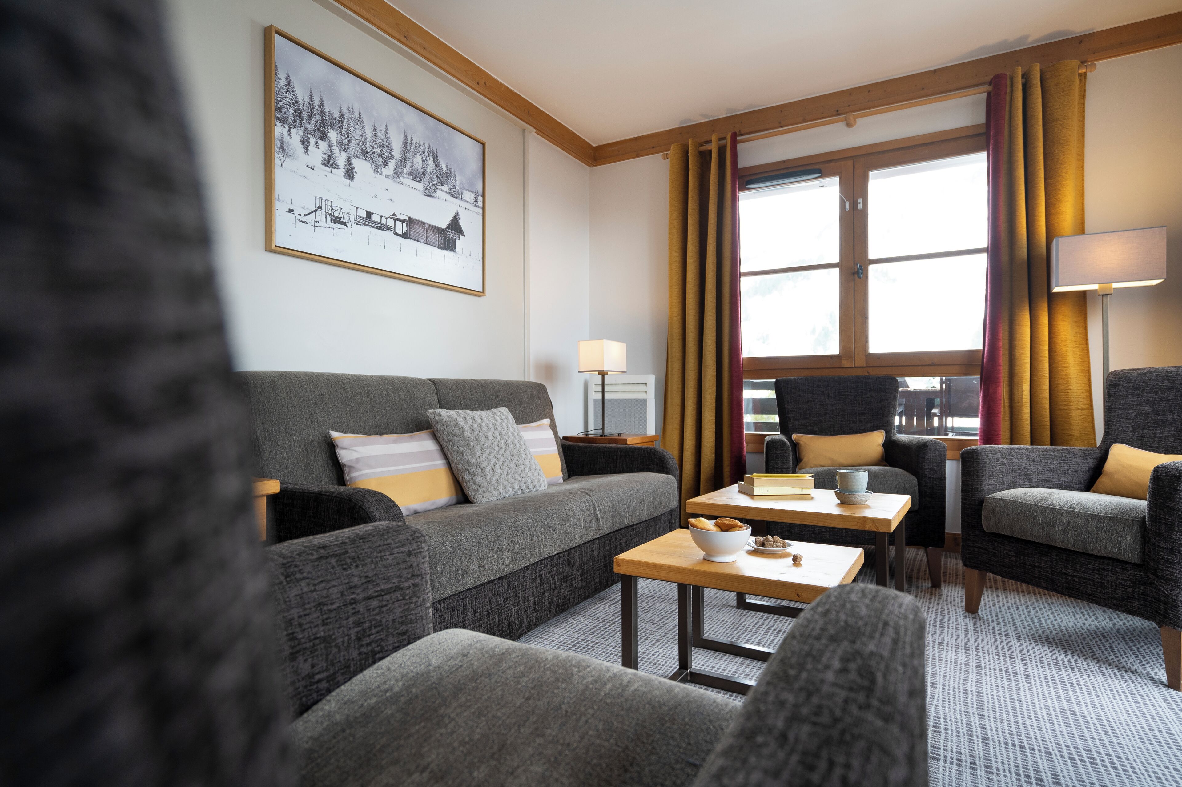A modern living room with a grey sofa, armchairs, a coffee table, and a lamp.